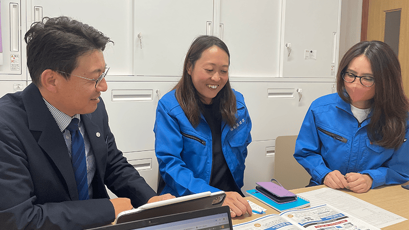 スーツの男性と作業着の女性が並んで座り話をしている様子