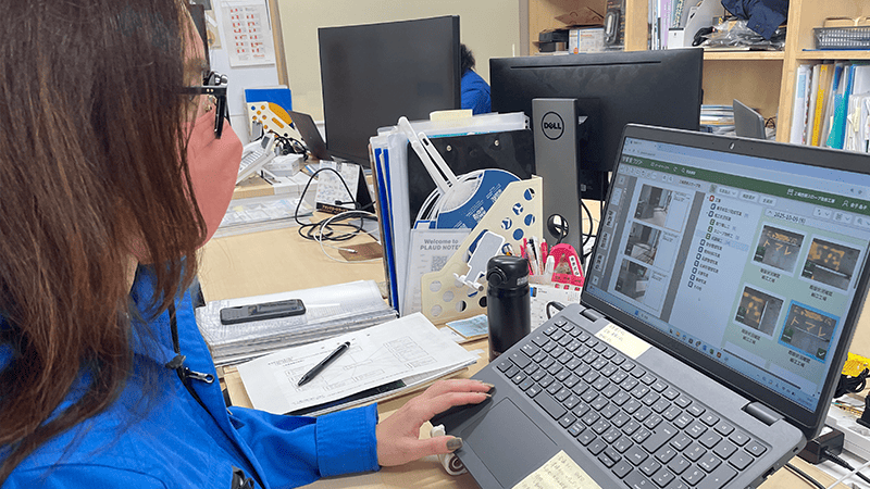 作業着の女性がパソコンで作業をしている様子