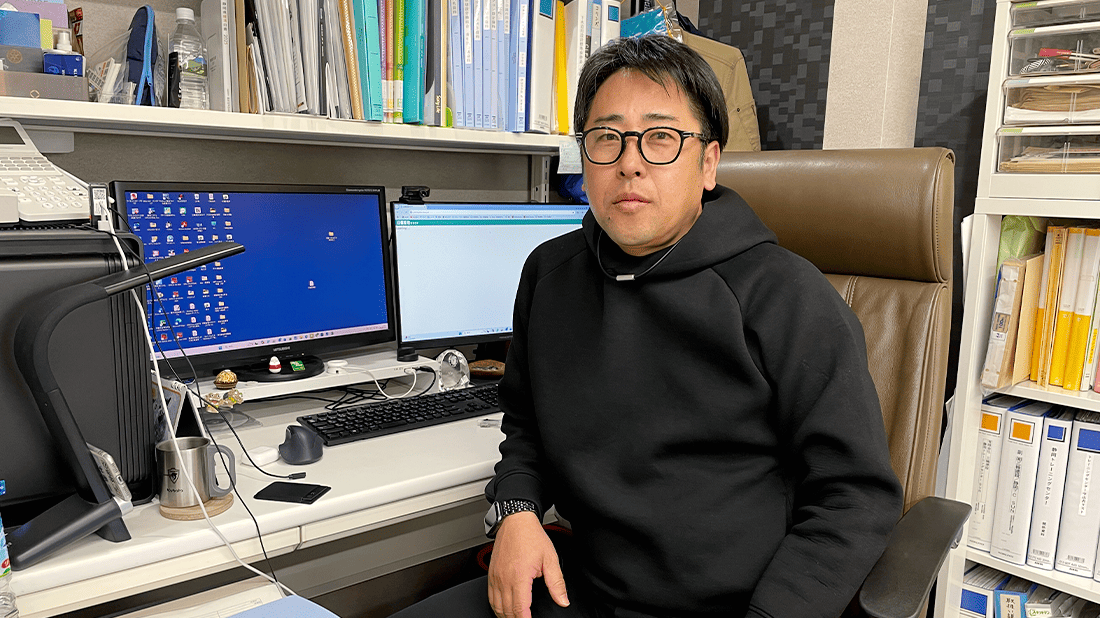 パソコンが置かれた机の前に座る男性の写真