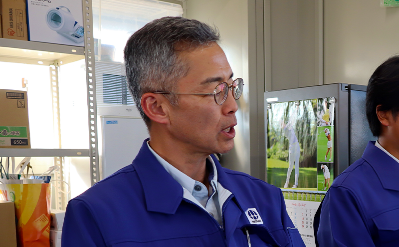 青い作業着を着た男性（金子氏）が話をしている写真