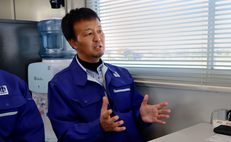 青い作業着を着た男性（山崎氏）が話をしている写真