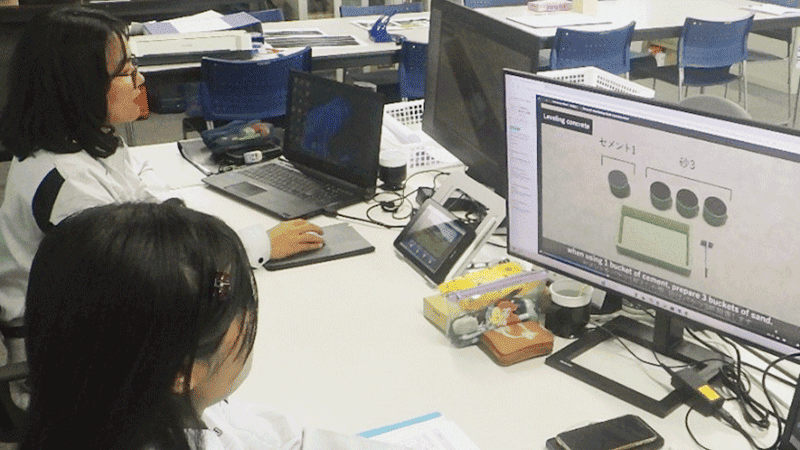 二人の作業着の女性がそれぞれモニターを見ている様子。