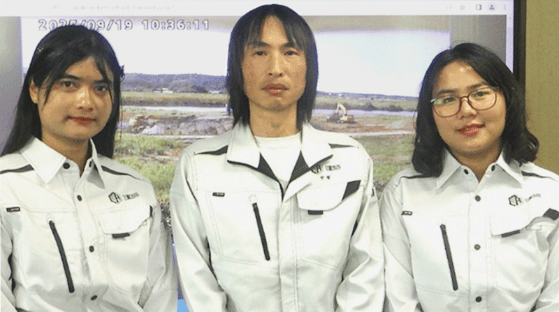 屋内で作業着を着た方が3人並んでいる写真。