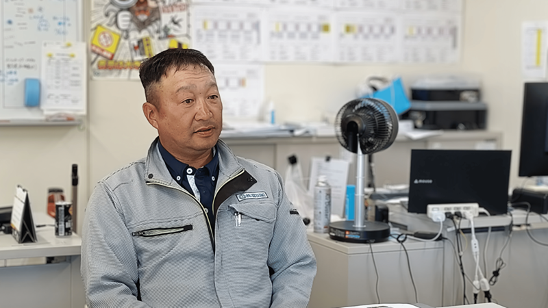 作業服を着た男性一人がインタビューを受けている様子