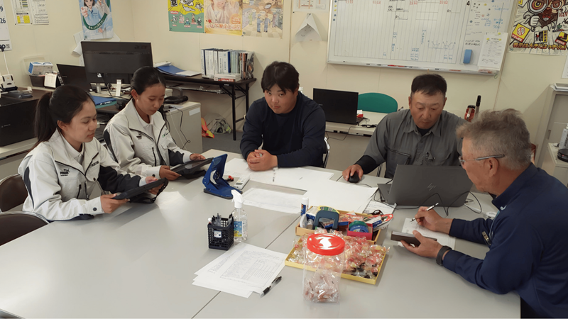 事務所で外国人社員と一緒に打合せをしている様子