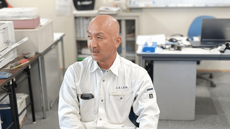 作業服を着た男性がインタビューを受けている様子