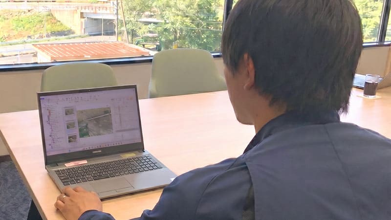 作業服を着た男性がPCで「SiteBox」を操作している様子