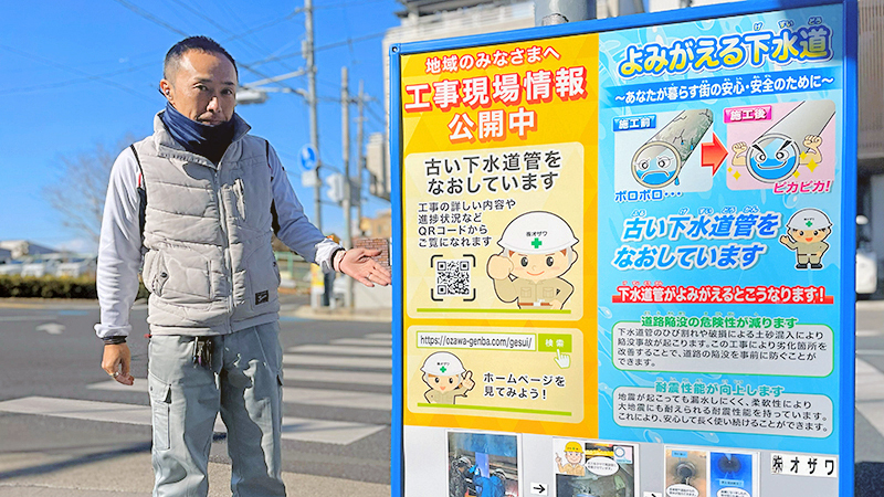 工事看板と横に立つ小沢様の写真