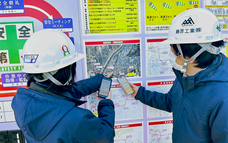 避難経路のパネルを指さす二人の人物