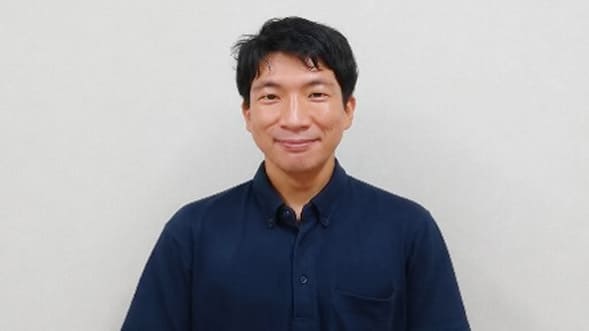 紺色の服を着た笑顔の男性の写真