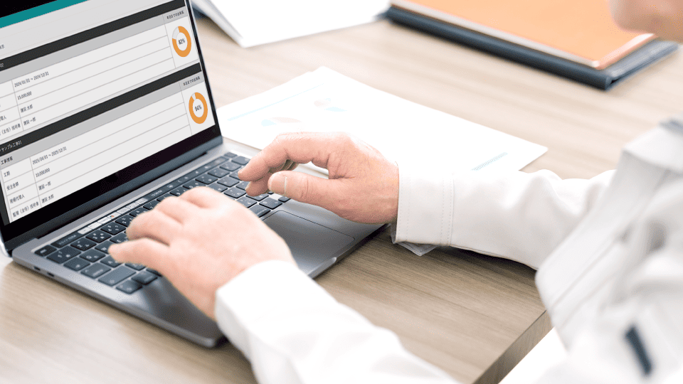 作業着の男性がパソコンで日報管理クラウドを使っている写真。